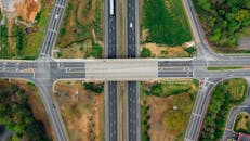 Highway junction with marking lines near green trees in suburb