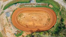 Drone view of bright open sandy pit near growing trees