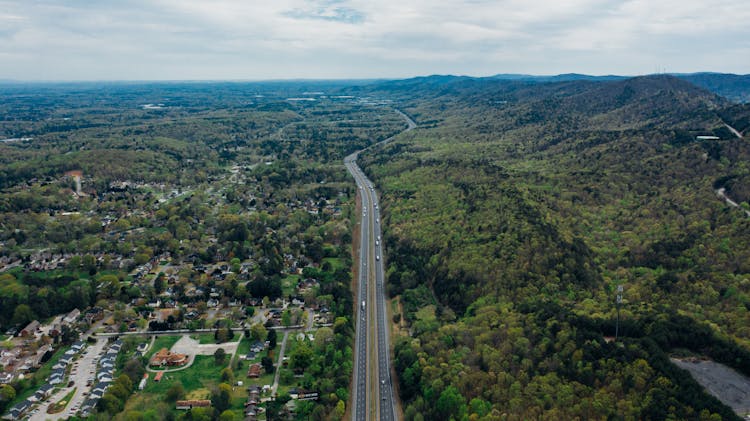 Highway Near Green Forest In City Under Cloudy Sky