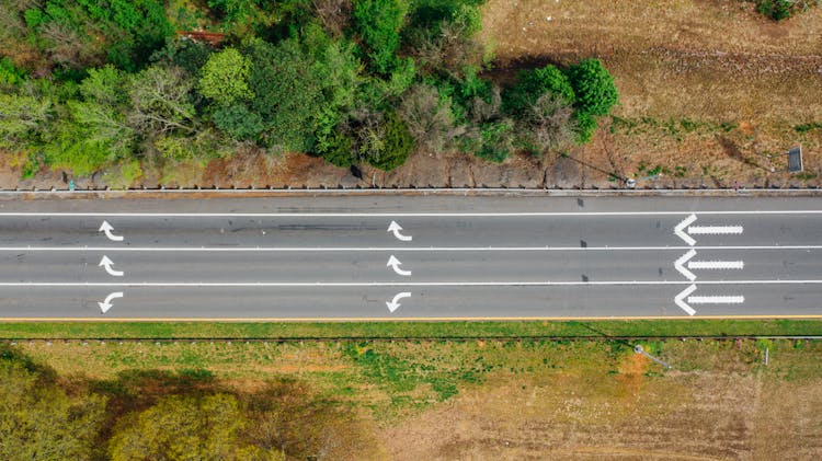 Aerial View Of Road With Arrows Near Colorful Trees