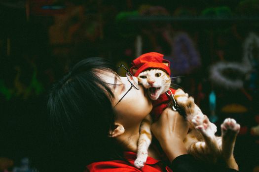 一个人深情地亲吻一只身着红衣的猫，营造出迷人而奇妙的瞬间