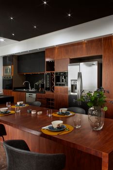 Sleek modern kitchen in Mexico City featuring wooden cabinetry, stainless steel appliances, and an elegant dining setup.