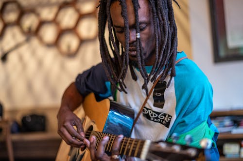 Focused black man playing guitar in studio