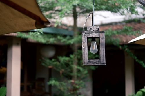 Free A rustic wooden lantern hangs in a serene, green garden setting, offering a tranquil outdoor ambiance. Stock Photo