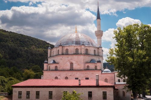 Free Beautiful mosque with distinctive architecture in Bulgaria, surrounded by lush forest under a cloudy sky. Stock Photo