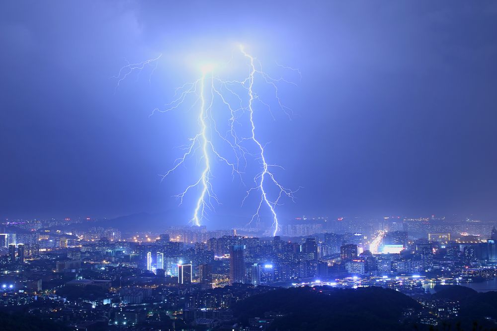 Dramatic lightning storm over a city skyline at night, representing the surge risk faced by Melbourne homes during the October–March storm season