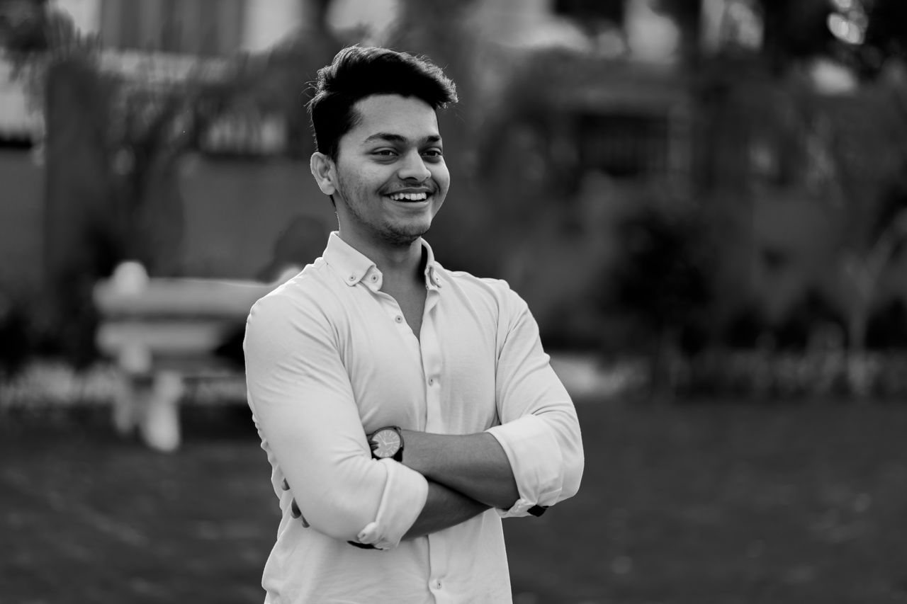 black and white of young cheerful guy in classic shirt standing with c