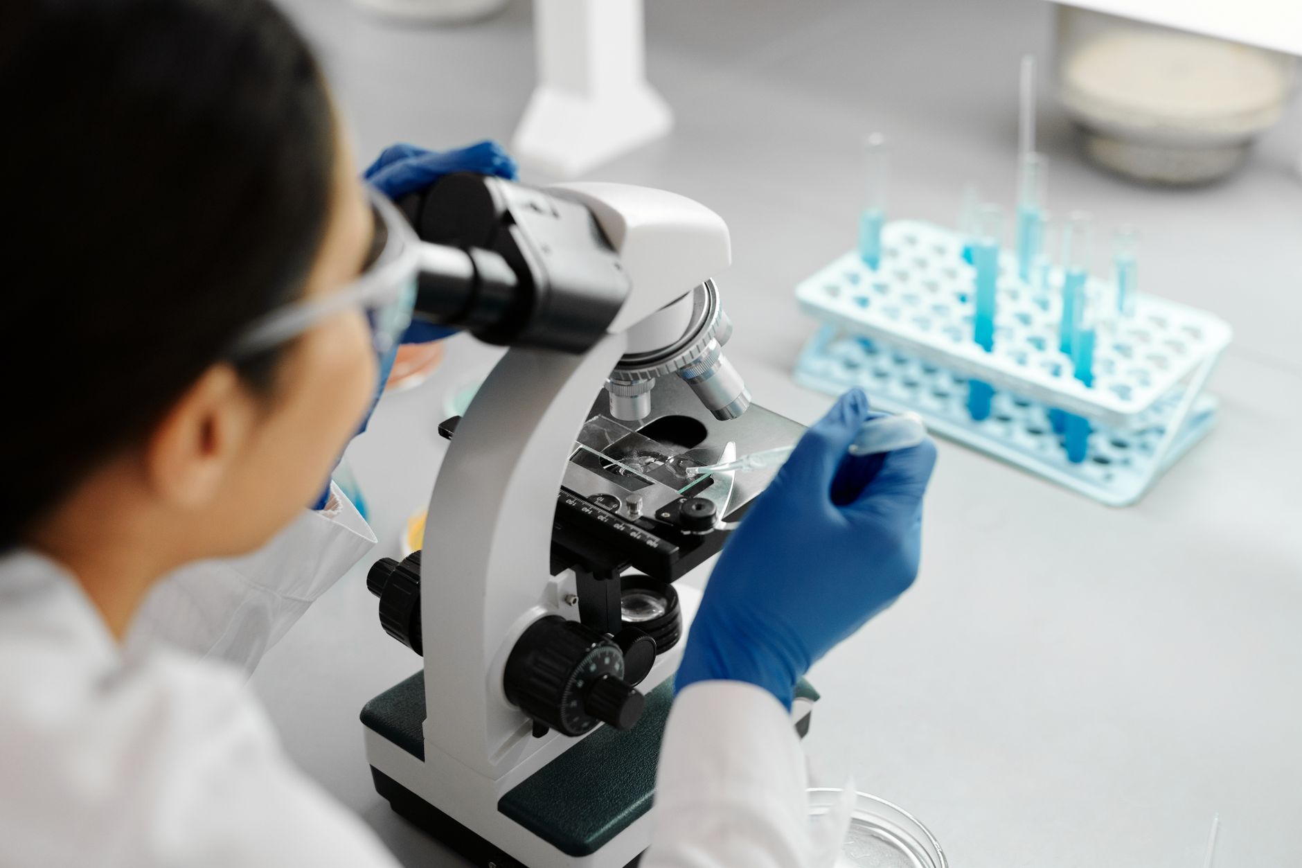 Scientist conducting research in a lab using a microscope and dropper.