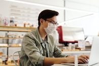 一名年轻人在现代咖啡馆里戴着口罩使用笔记本电脑
