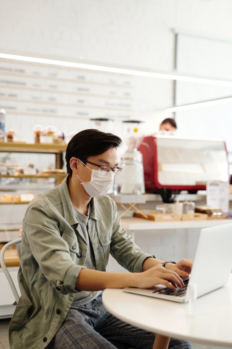 Photo Of A Man In A Green Jacket Working On His Laptop