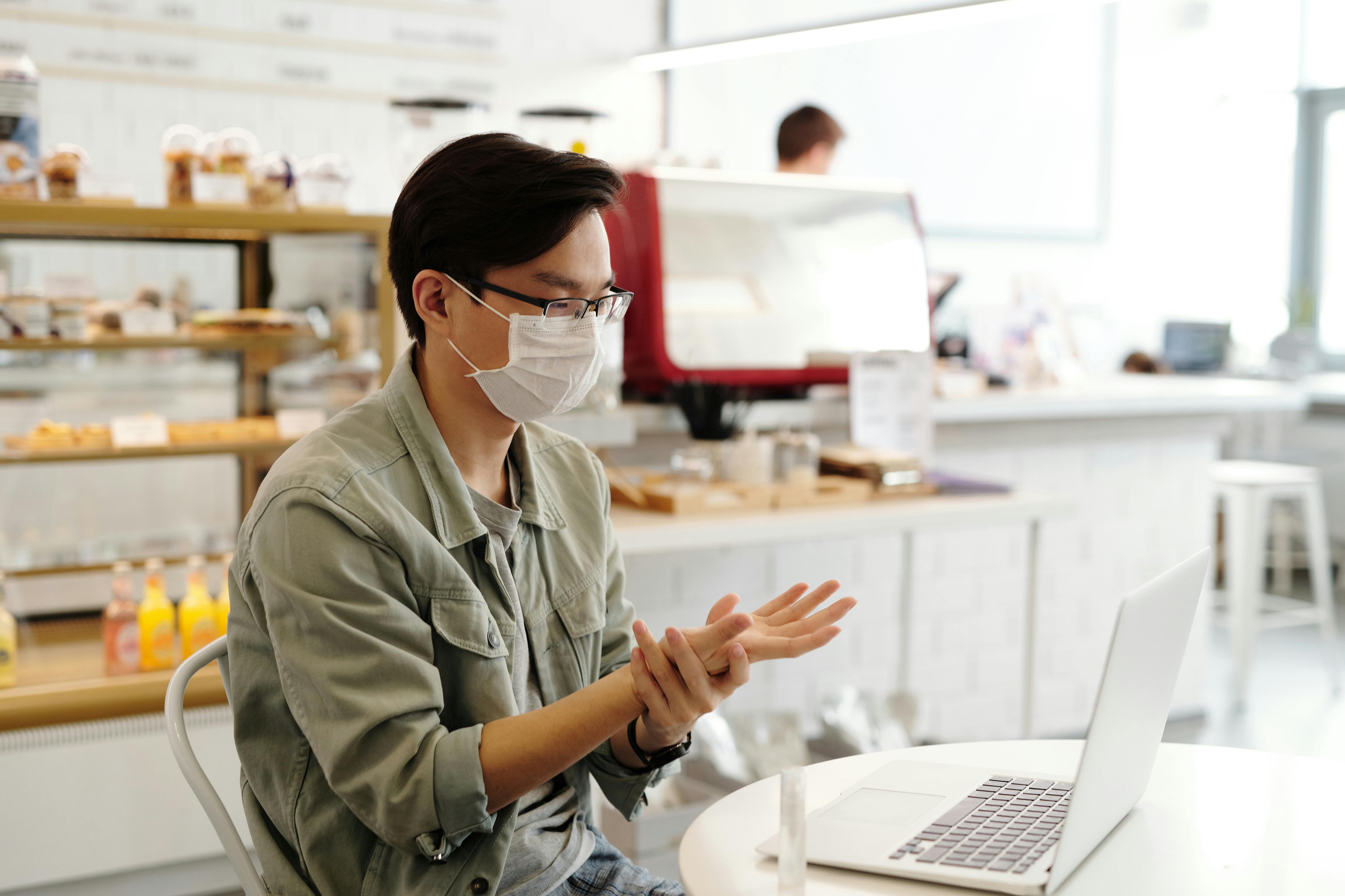 photo of a man with a face mask holding his wrist