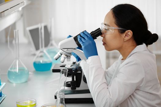 女科学家在实验室里通过显微镜检查样本进行研究