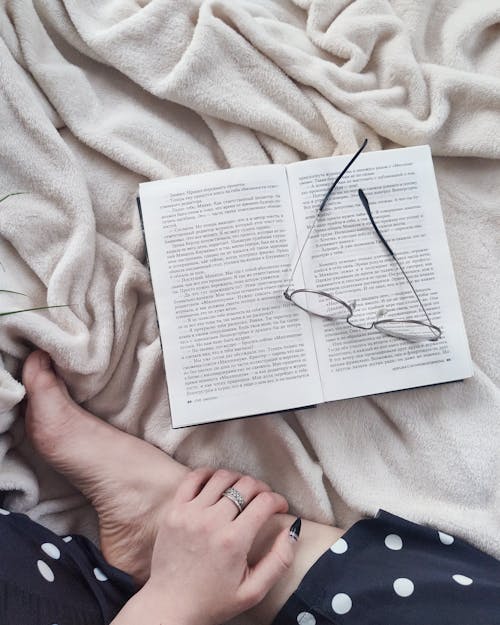 Femme De Culture Reposante Sur Une Couverture Douce Avec Livre