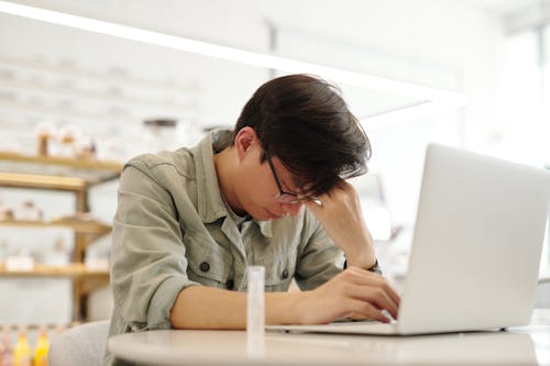 A Man Looking Sick while Working with His Laptop