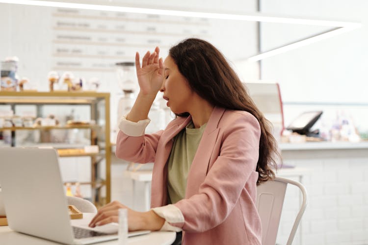 A Woman Sneezing While Working On Her Laptop