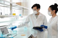 两名科学家穿着实验室外套，在实验室里检查计算机上的数据