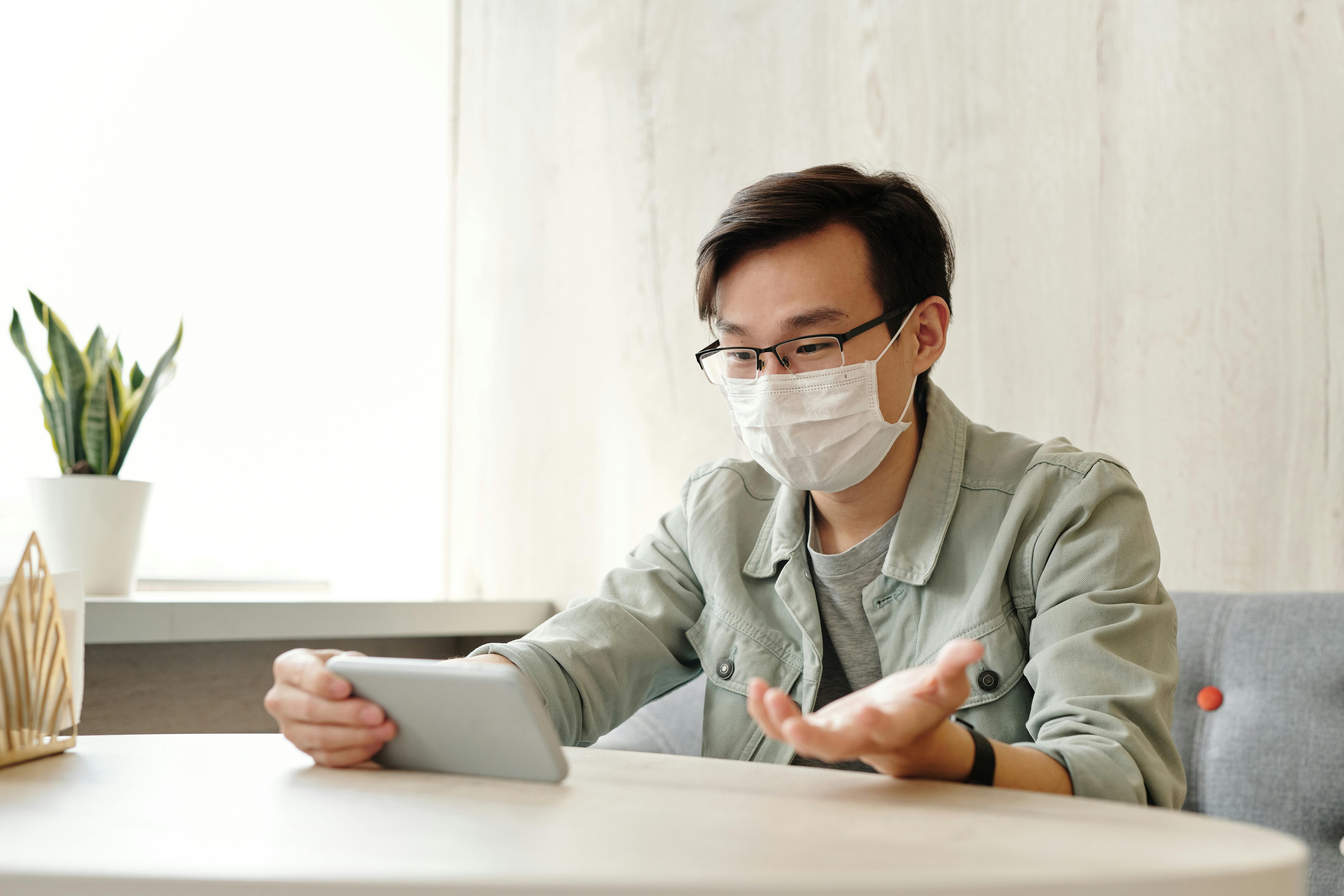 man wearing face mask while having a video call