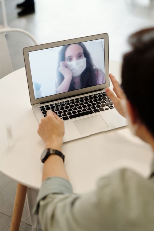 Free Woman on a video call wearing a face mask, representing remote connections in the pandemic era. Stock Photo