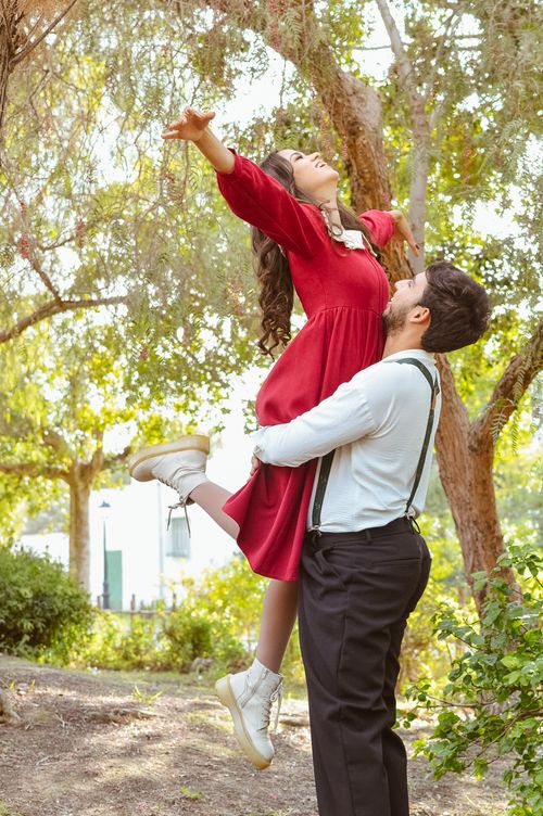 Free Joyful couple dancing in nature, with greenery and sunlight creating a romantic setting. Stock Photo