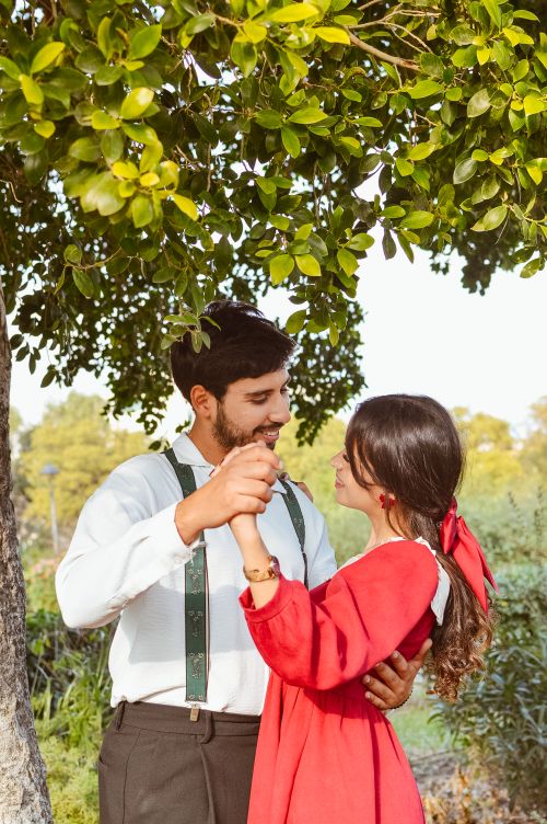 Free A loving couple shares a romantic dance under a lush green tree on a sunny day. Stock Photo