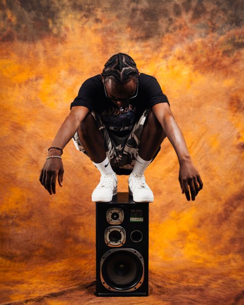 Free Dynamic studio shot of a man crouching on a speaker against a vibrant backdrop. Stock Photo