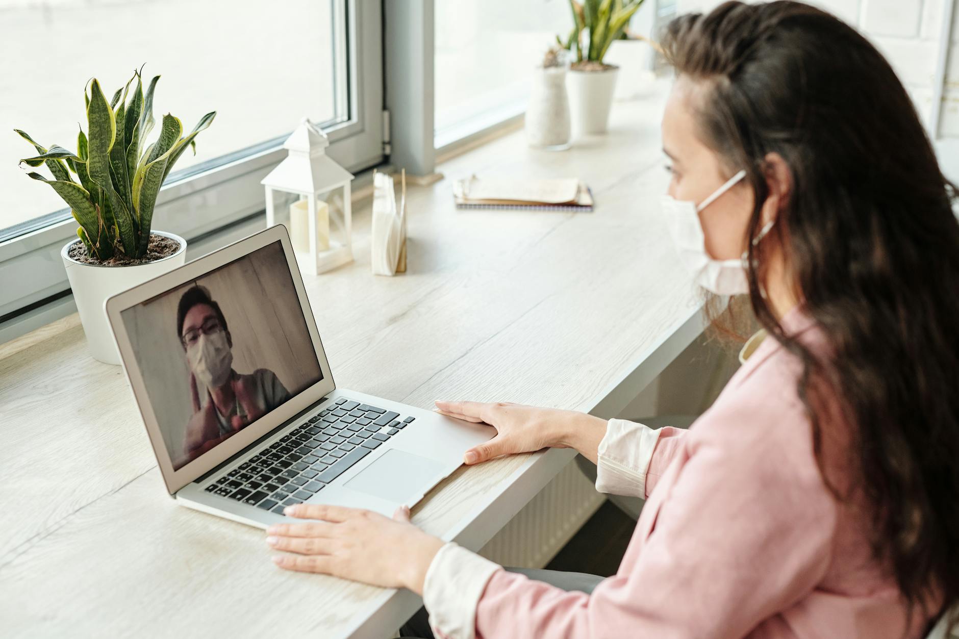 Uma mulher de máscara em uma chamada em vídeo com um homem de máscara, fazendo uma pesquisa de mercado online.