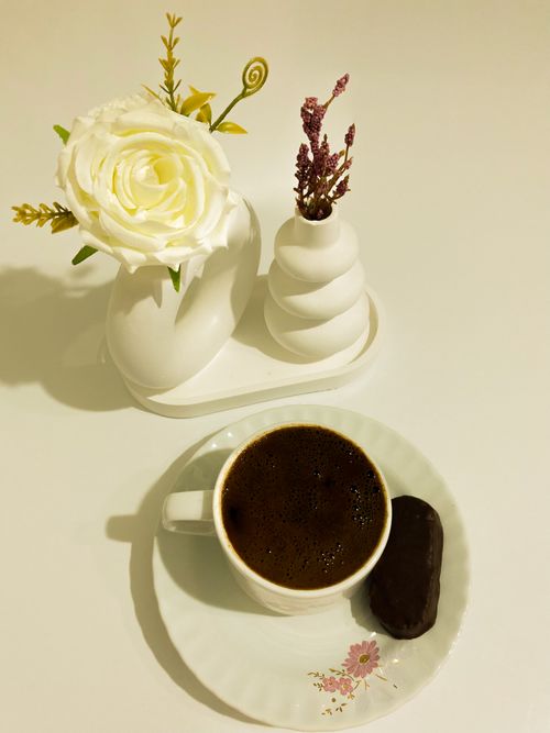 Free Coffee cup with floral decor next to vases on a white table, creating a serene, minimalist vibe. Stock Photo