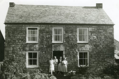 Фотография четырех женщин, стоящих перед домом в оттенках серого