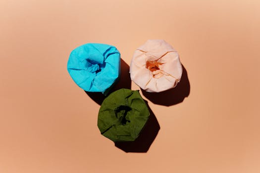 Vibrant blue, green, and peach toilet paper rolls on a peach background.