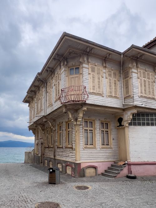 Free A vintage wooden mansion with intricate details by a seaside location under an overcast sky. Stock Photo