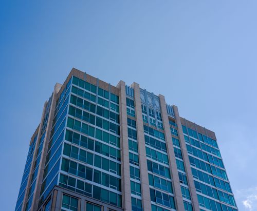 Free Modern skyscraper with glass facade rising against a clear blue sky, showcasing urban architecture. Stock Photo