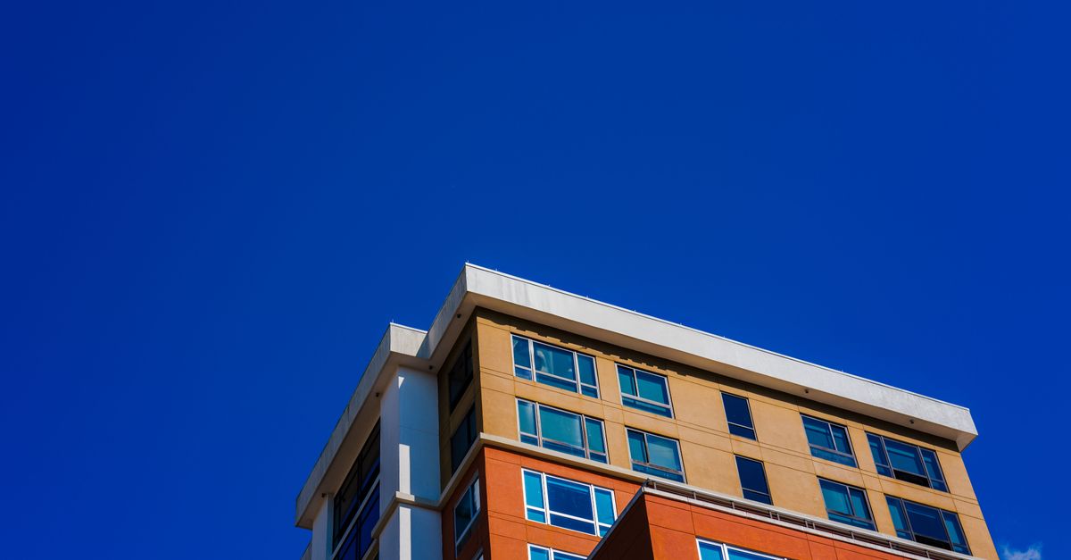 A contemporary apartment building with colorful facade against a clear blue sky.