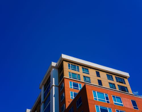 Free A contemporary apartment building with colorful facade against a clear blue sky. Stock Photo