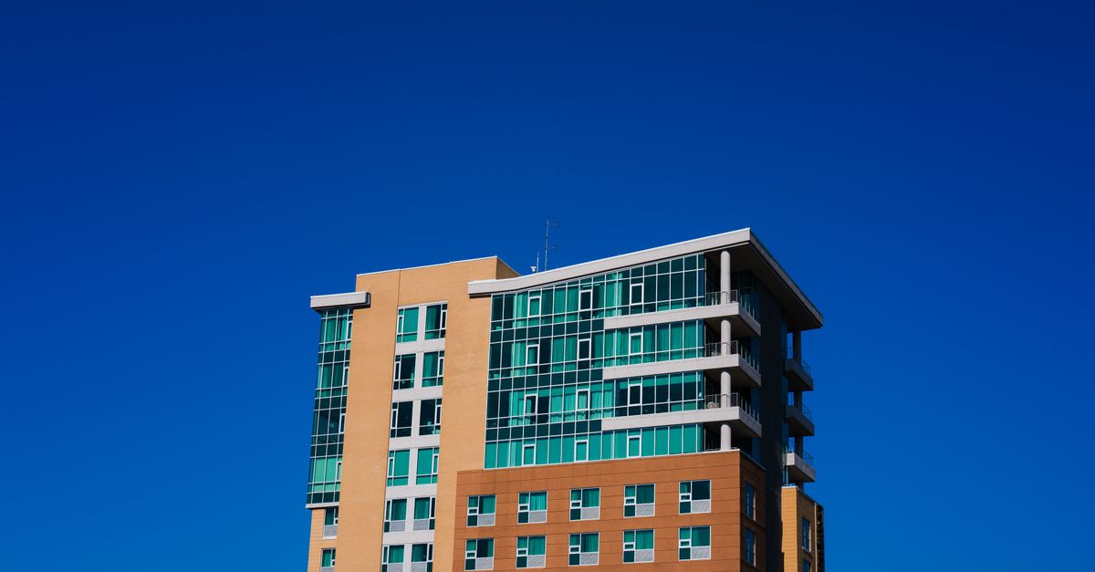 A modern high-rise building stands tall against a vivid blue sky, showcasing contemporary architecture.