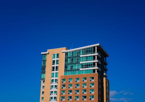 Free A modern high-rise building stands tall against a vivid blue sky, showcasing contemporary architecture. Stock Photo