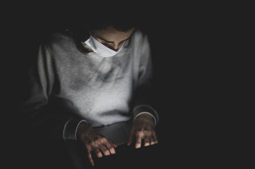 Free Man With Face Mask Using Laptop In The Dark Stock Photo