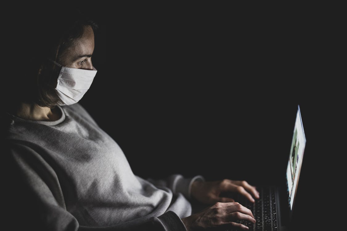 Free Woman Wearing Face Mask Using Black Laptop Computer Stock Photo