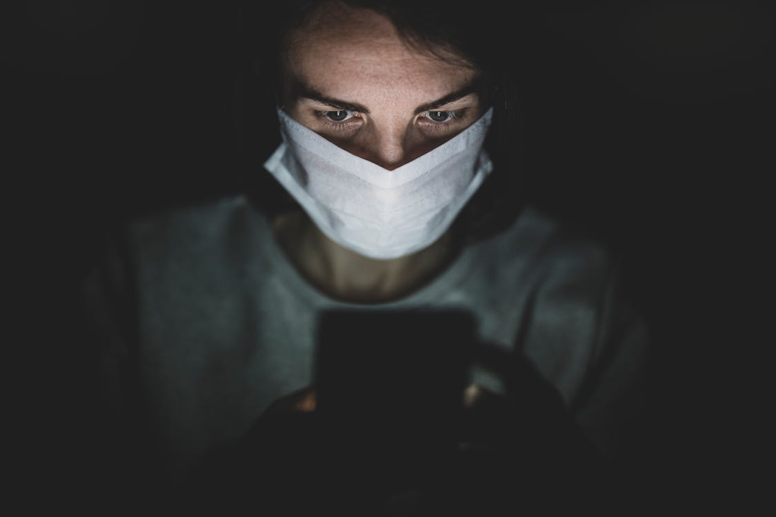 Free Man Wearing Face Mask Using His Phone In The Dark Stock Photo