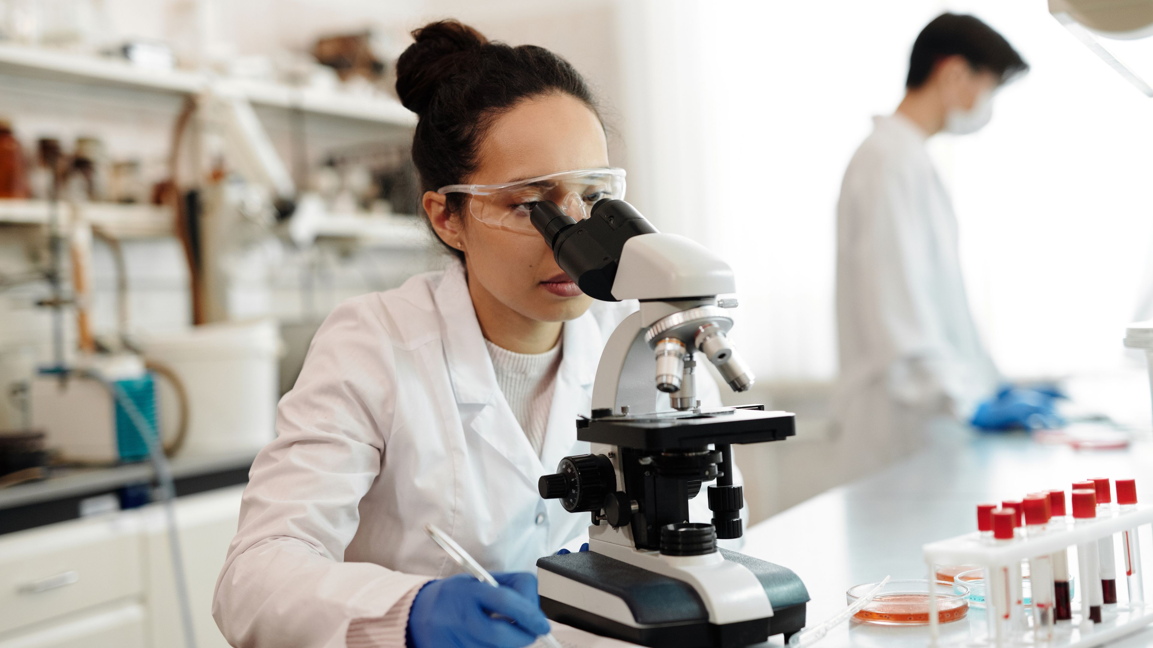 Female scientist in a white lab coat performing laboratory analysis at the bench