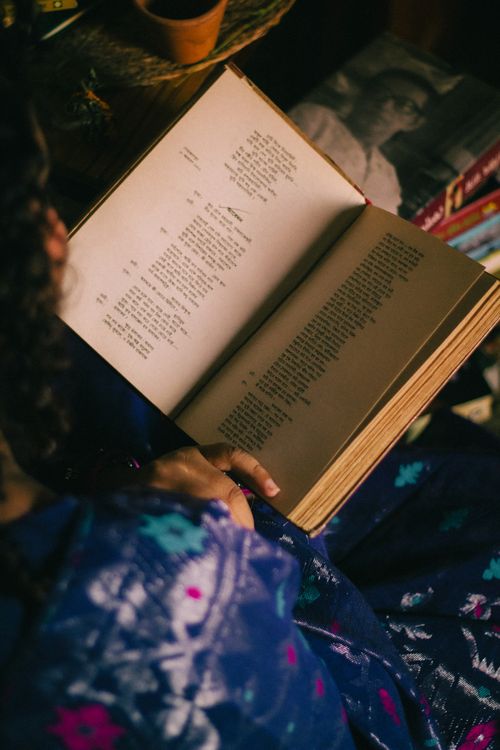 Free A woman immersed in reading a poetry book, creating a warm and cozy ambiance. Stock Photo