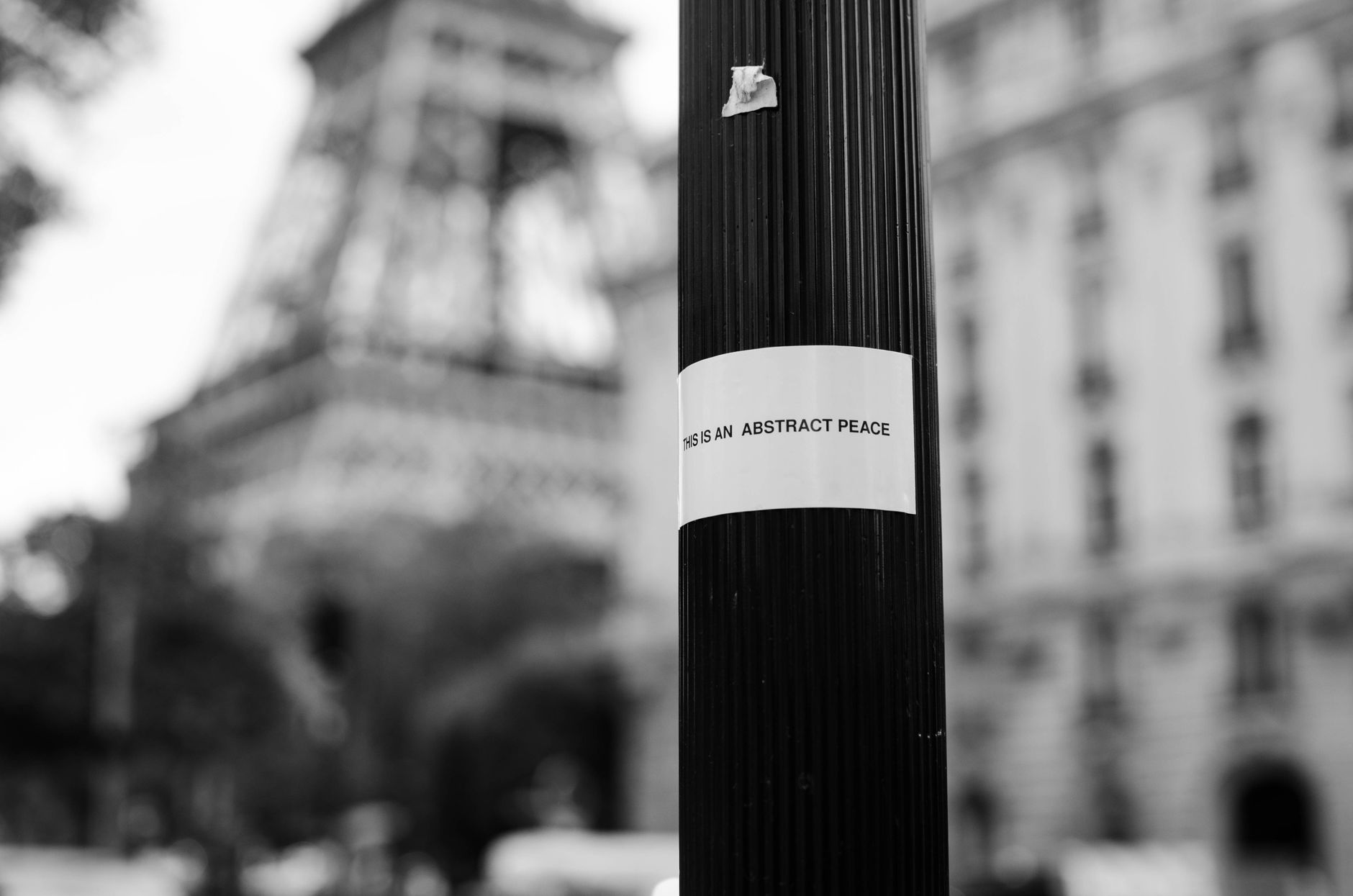 Black and white detail of metal street pole with adjusted inscription against Eiffel tower in Paris