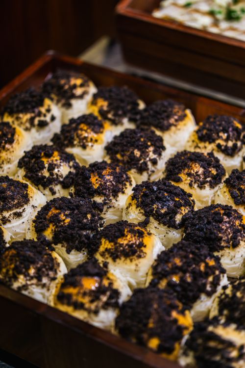Free Delicious pastries covered with rich chocolate crumbles displayed in a wooden tray. Perfect for dessert lovers. Stock Photo