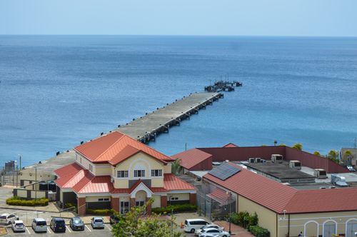 Free A scenic view of a coastal pier and red-roofed buildings overlooking a tranquil blue sea. Stock Photo