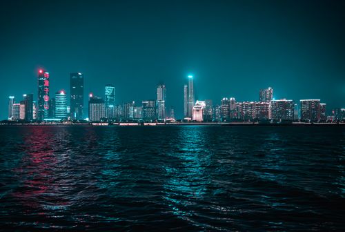 Free A captivating night skyline with neon reflections over water, showcasing modern architecture. Stock Photo