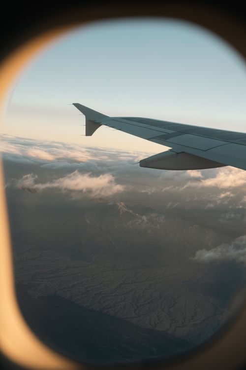Free A breathtaking aerial view of mountains through an airplane window during flight. Stock Photo