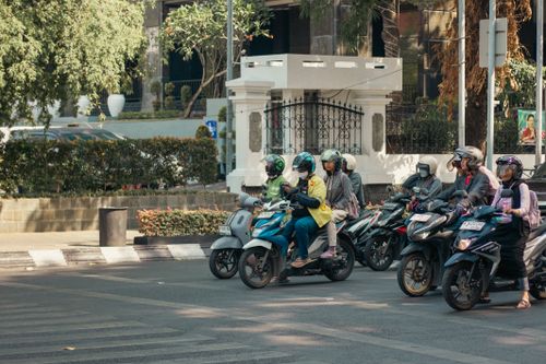 Free A group of motorcyclists wait at a traffic light in a busy city intersection during the day. Stock Photo