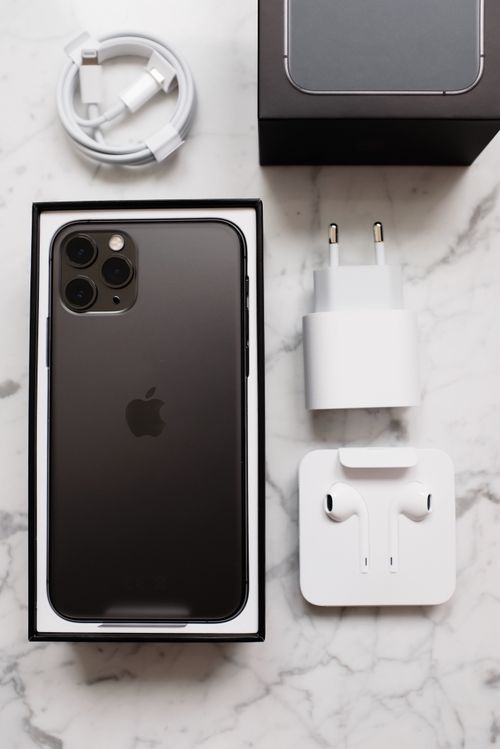 Free Top view of black smartphone in box package and usb wire for battery charging and wireless earphones on marble table Stock Photo