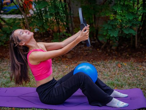Free A woman practicing Pilates with a ring and exercise ball outdoors in Jakarta. Stock Photo