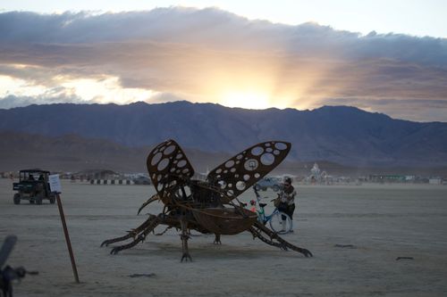 Free Dramatic sunset over art sculpture in desert festival setting. Stock Photo