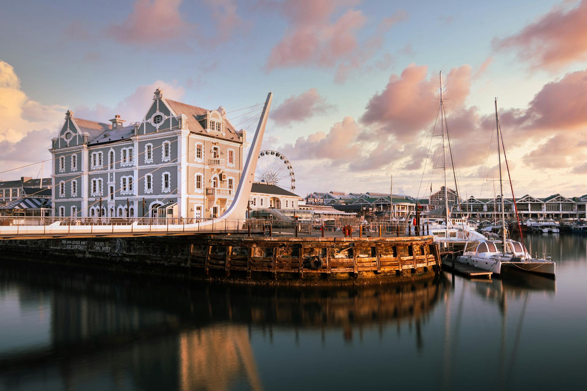 Captivating view of Cape Town's marina with docked sailboats and historic architecture at sunset.